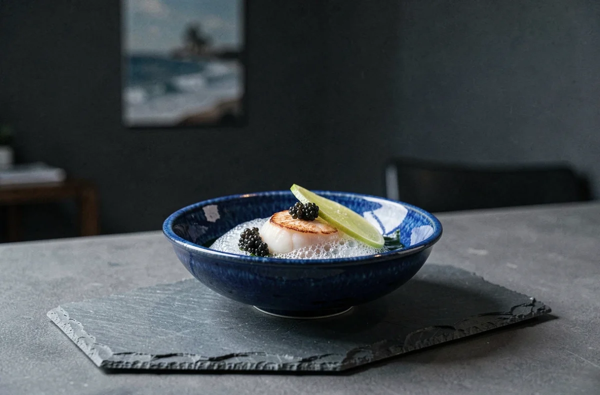 Saint-Jacques poêlée sur mousse d'algues et perles de caviar dans un bol céramique bleu profond, cours d'omakase marin au restaurant Abysse rue La Boétie à Paris